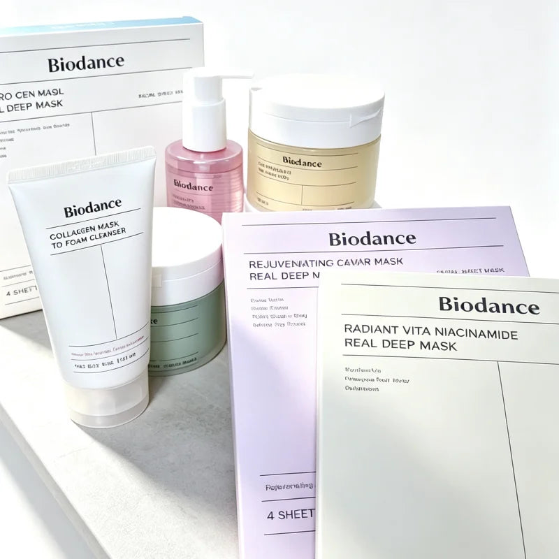 A collection of Biodance skincare products arranged on a light surface, including a collagen mask to foam cleanser tube, a pink serum bottle, a beige mask jar, sheet masks, and masks in their boxes.