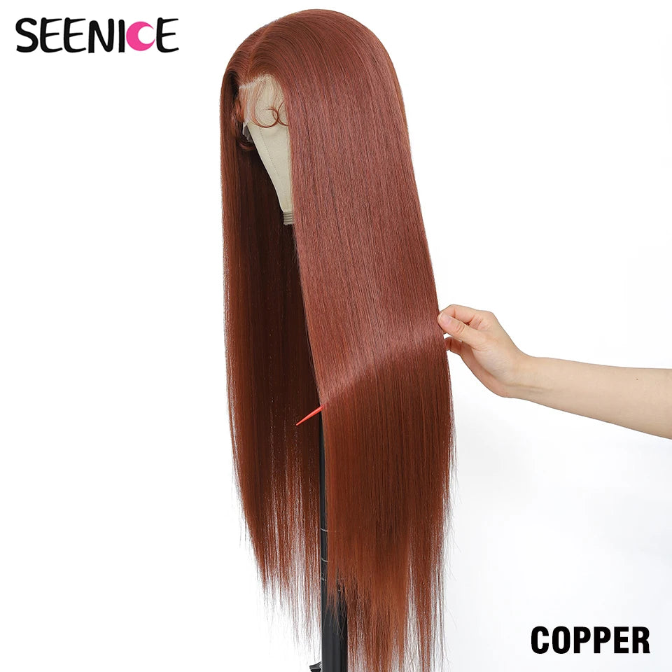 A long, straight wig in a copper auburn shade displayed on a mannequin stand, with a human hand holding a section of the hair to show its texture and weight. The brand 'SEENICE' is visible in the top left corner, and the color 'COPPER' is labeled in the bottom right.