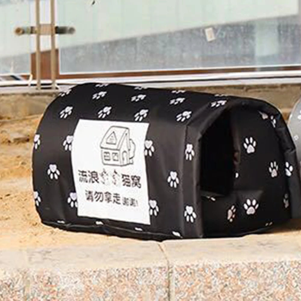 Black pet bed with white paw prints and a label on a stone surface.