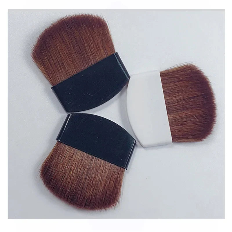 Three makeup brushes with brown bristles and black or white handles on a light gray background.