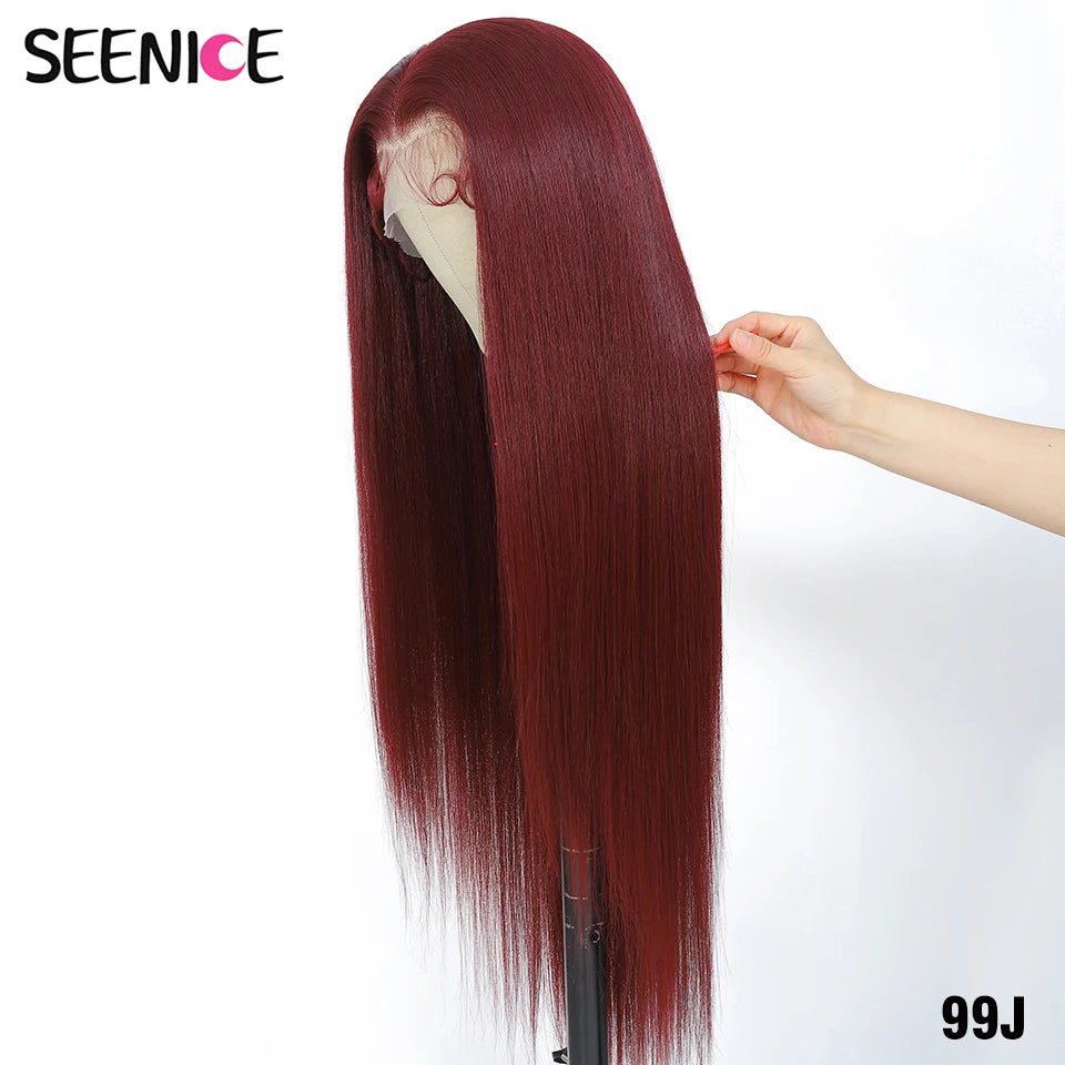 A long, straight, deep auburn-red wig displayed on a mannequin head stand, with a human hand holding a section of the hair to show texture and volume. The brand name 'SEENICE' is visible in the top left corner, and the style code '99J' is in the bottom right.