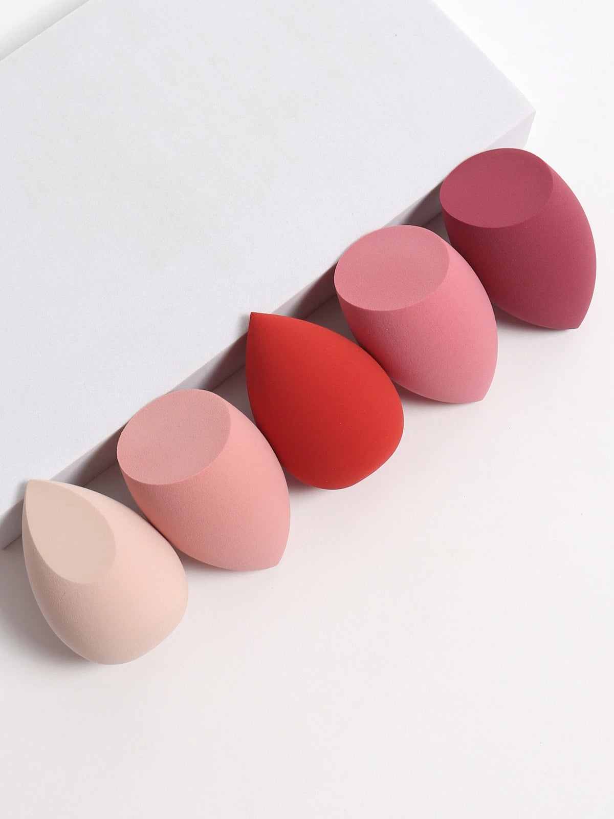 Set of pink and red makeup sponges on a white background