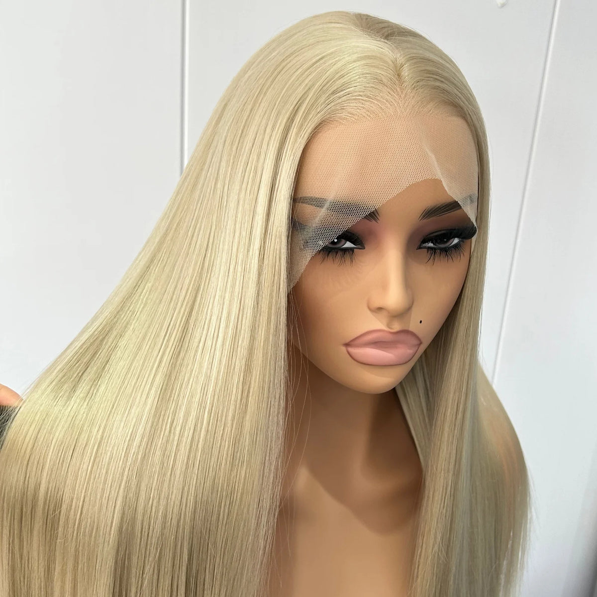 A straight, shoulder-length blonde wig with a realistic part and wispy bangs, displayed on a mannequin head against a plain light background.