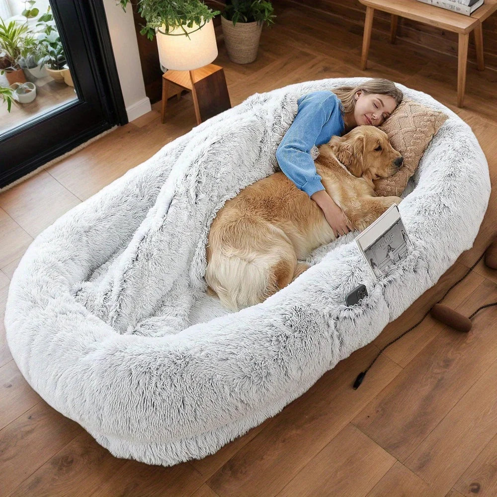 Woman and dog in a large fluffy pet bed on a wooden floor.