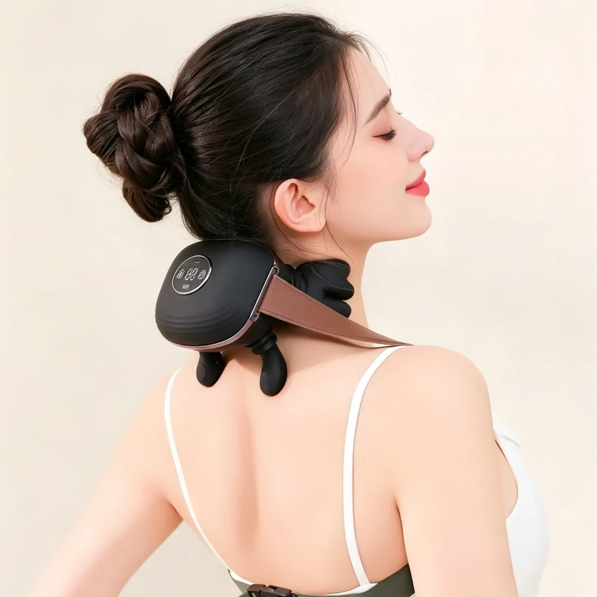 Woman using a neck and shoulder massager on a plain background