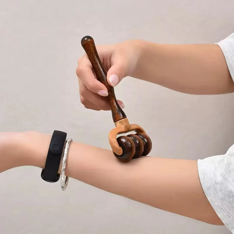 Hand using a wooden massage roller on an arm against a neutral background