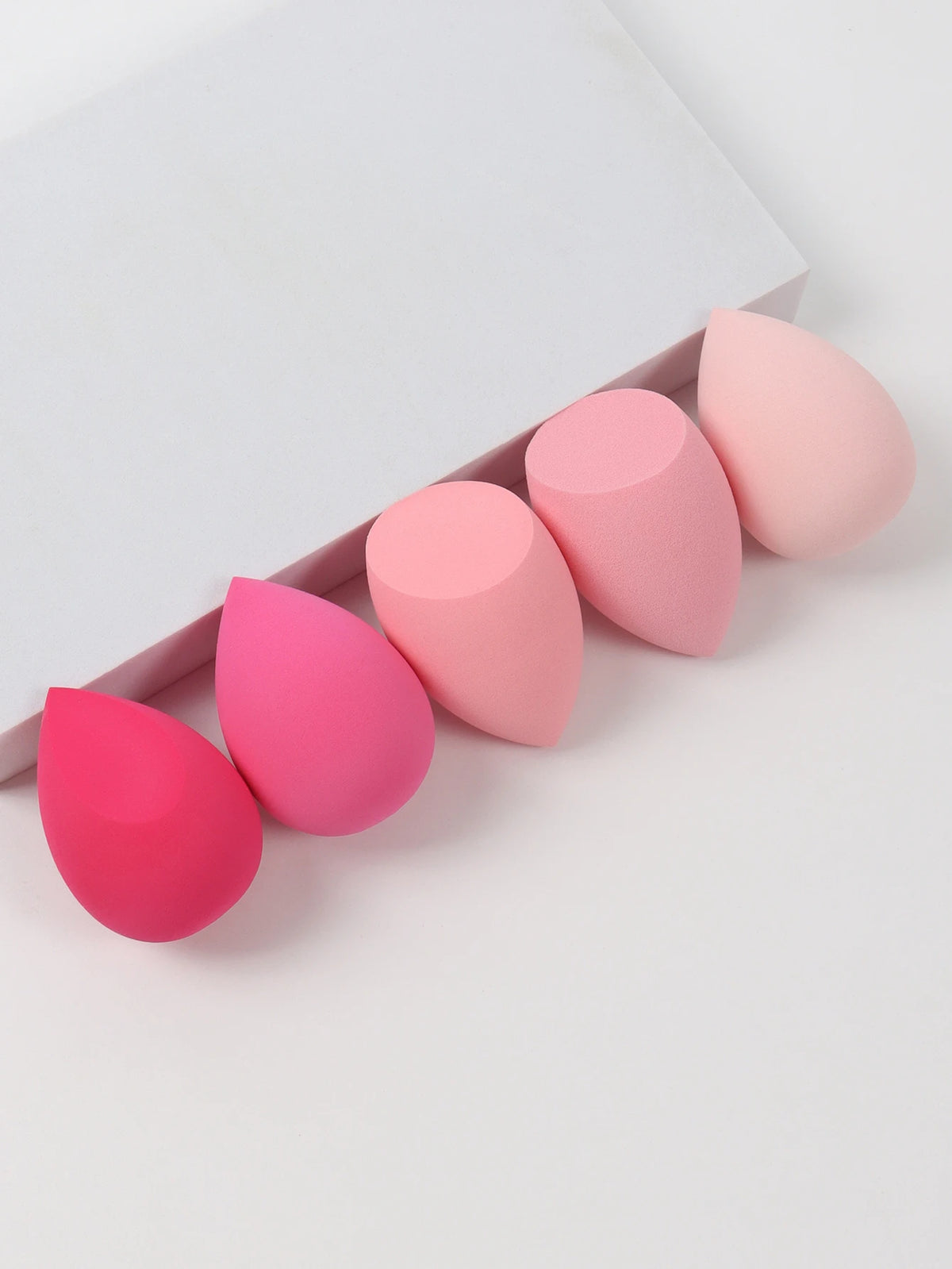 Set of pink makeup sponges on a white background
