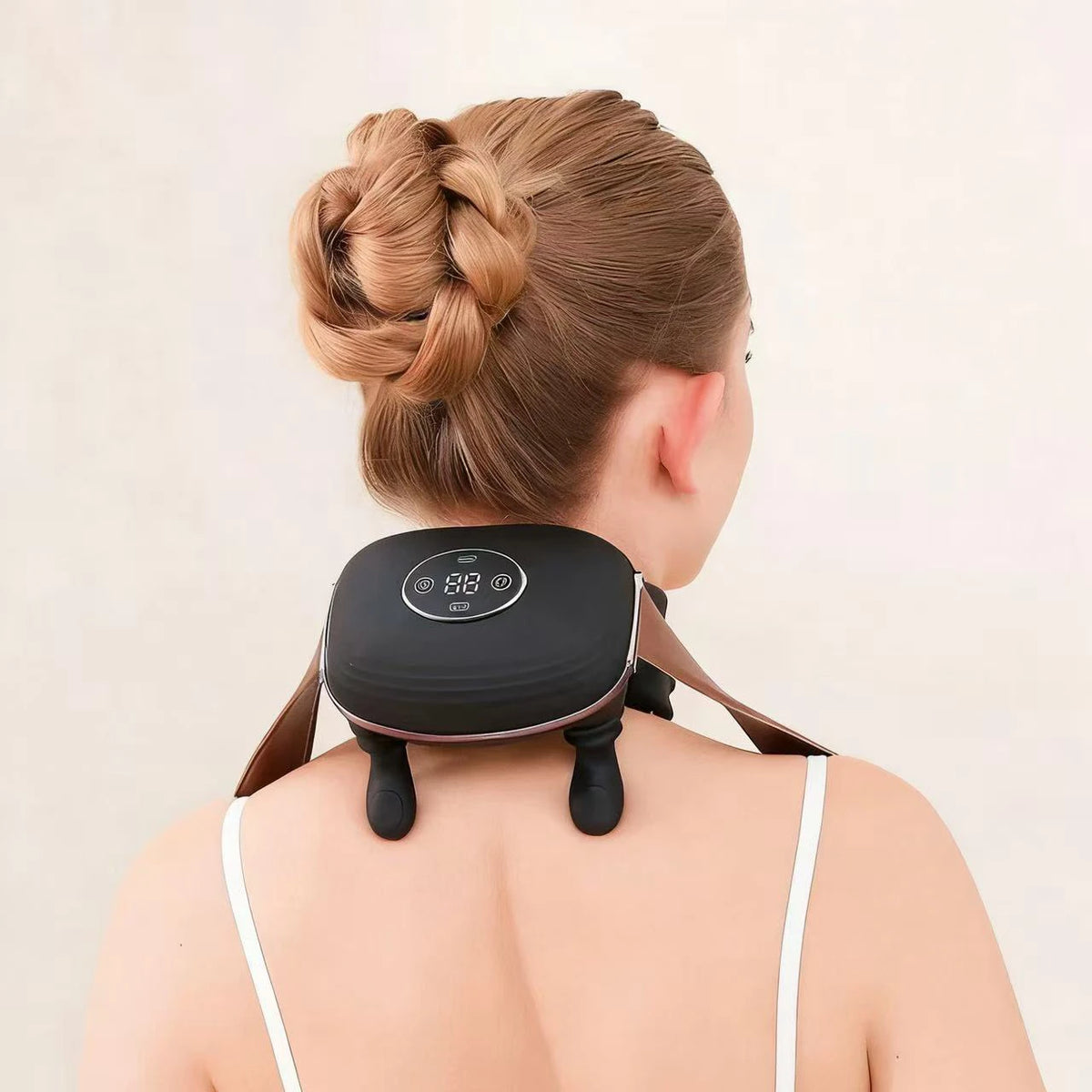 Person using a neck and shoulder massager with a beige background