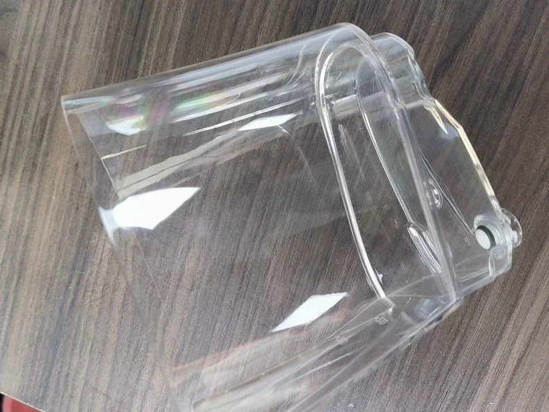 A clear plastic cup or tumbler with a handle, shown at an angle on a dark wood-grain surface.