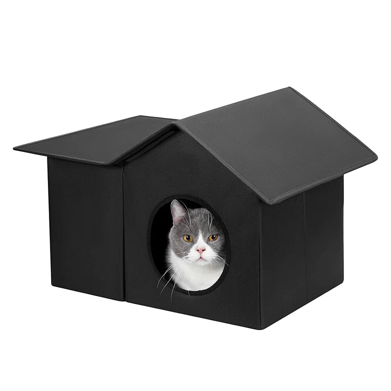 A black house-shaped cat bed with a gray and white cat peeking out from the circular entrance, set against a plain white background.