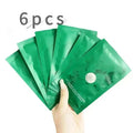 Hand holding six green facial mask packages with a white background