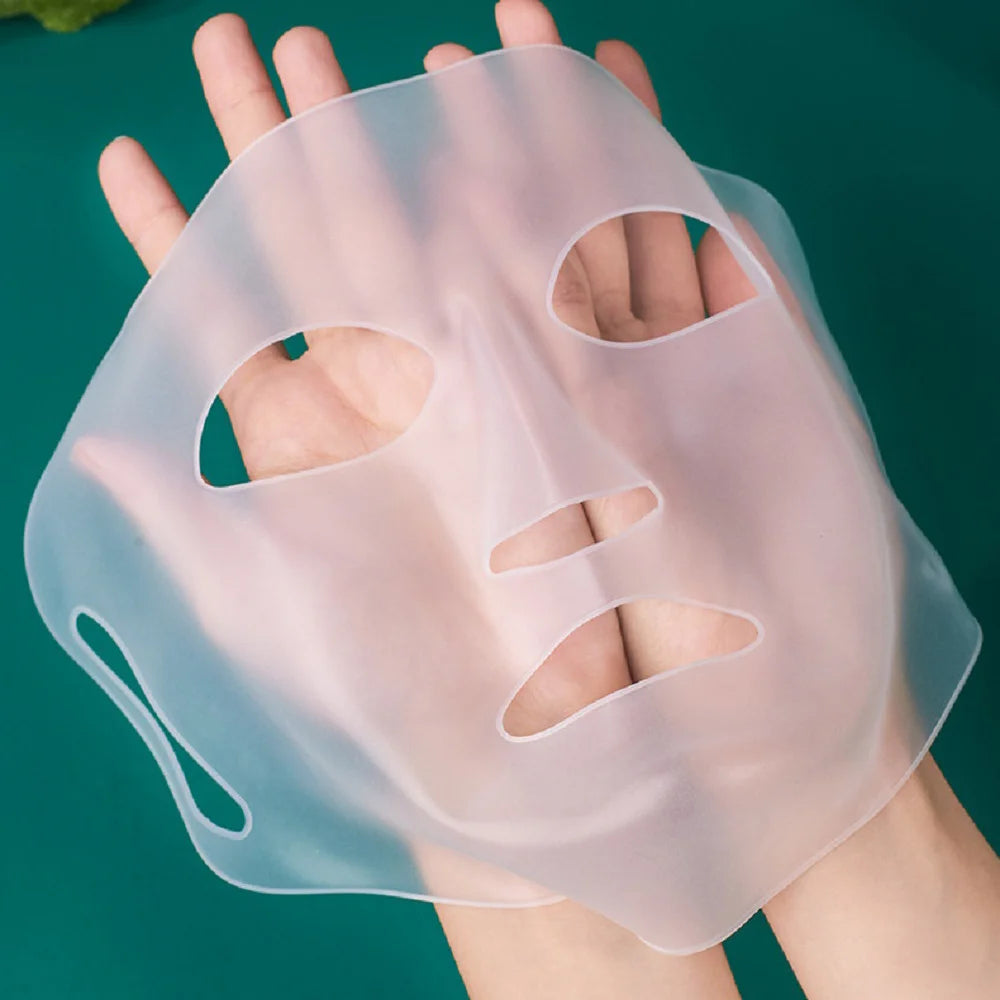 Silicone face mask held by a hand against a green background