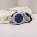 Retractable dog leash with purple handle and blue reel on a white surface with white fabric.