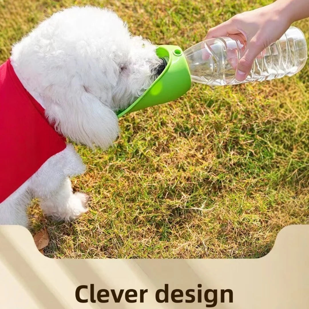 A small white dog wearing a red shirt drinks water from a clear plastic bottle attached to a green pet waterer outdoors on grass. A hand holds the bottle, and the text 'Clever design' appears at the bottom.