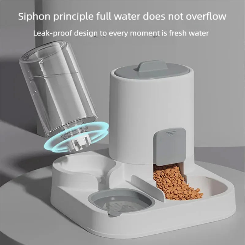 A white automatic pet feeder with a clear water reservoir shown tilted to demonstrate the siphon principle, with kibble falling into a bowl. Text at the top reads, 'Siphon principle full water does not overflow' and 'Leak-proof design to every moment is fresh water.