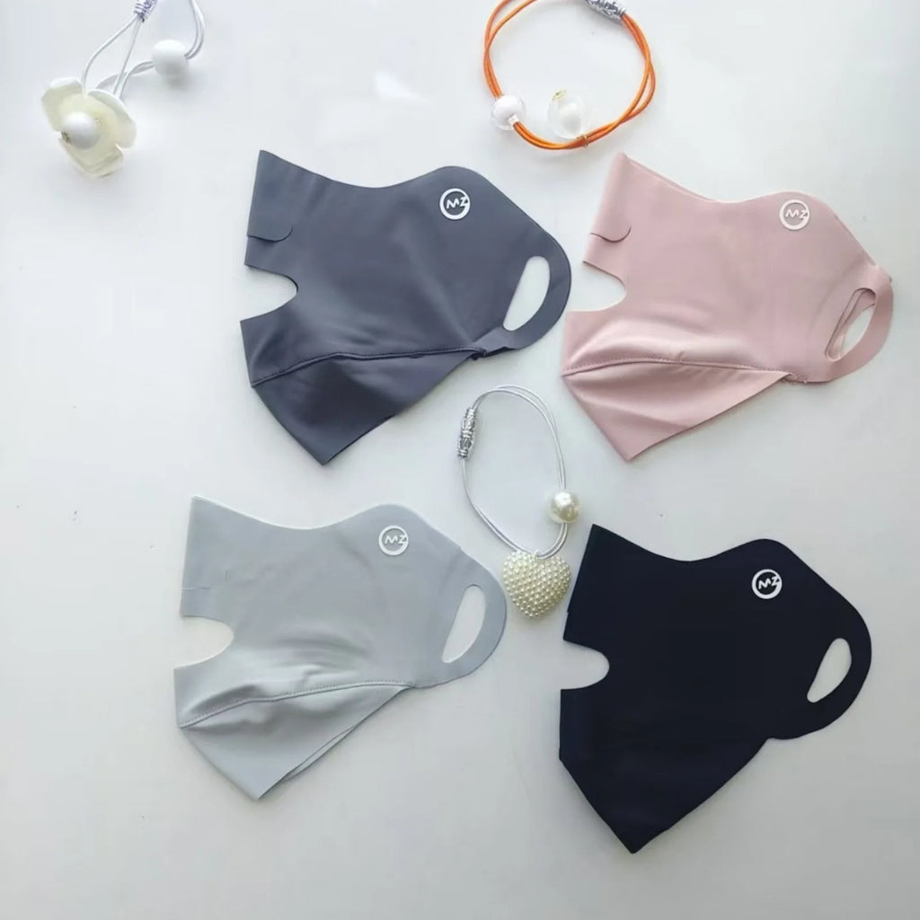 Four face masks in gray, pink, black, and blue on a light background with small accessories.