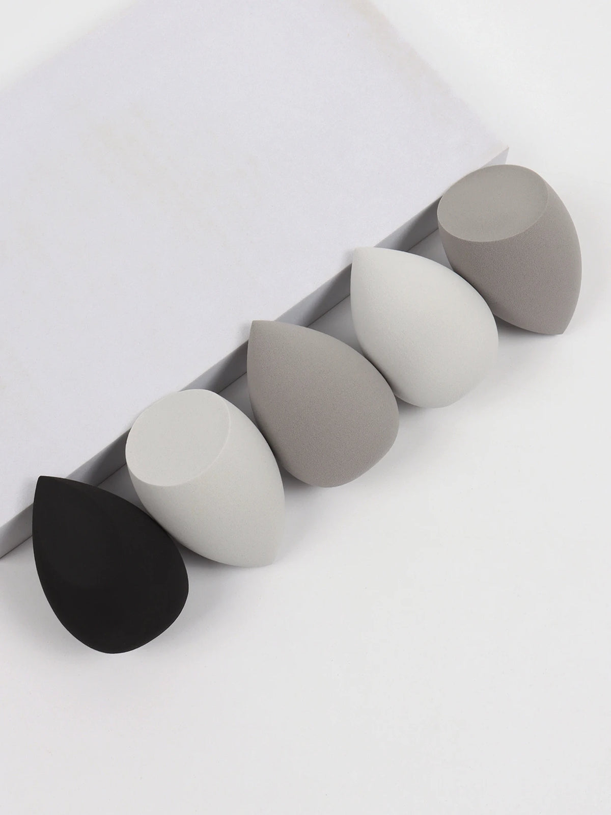 Set of five silicone sponges in black, gray, and white on a white background