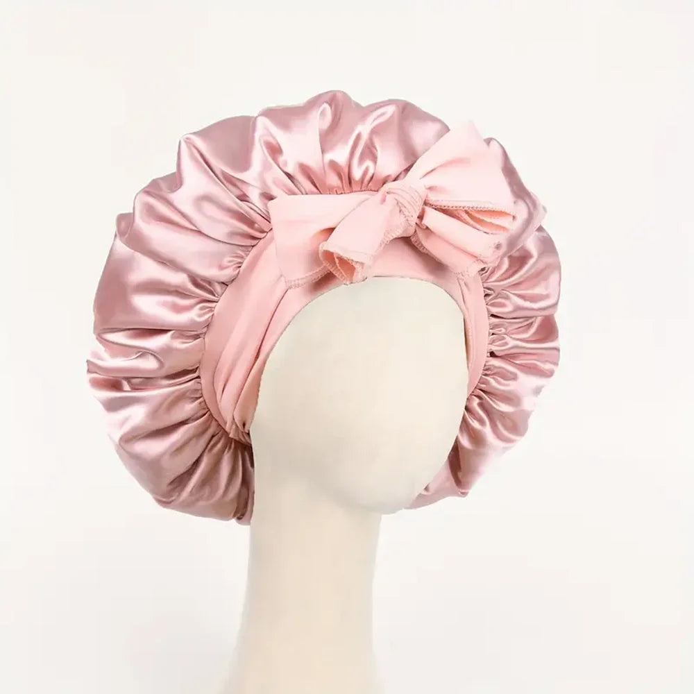 Pink satin bonnet with a bow on a mannequin head against a light pink background
