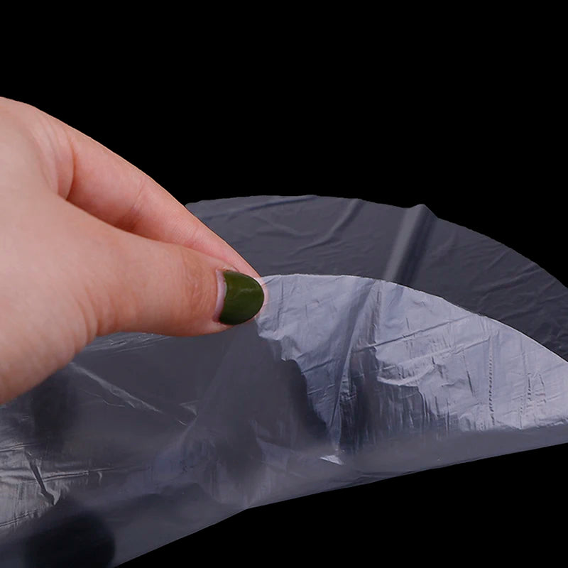 Hand holding a crumpled gray plastic bag against a black background