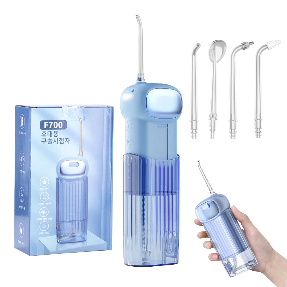 Blue dental water flosser with packaging, nozzles, and a hand holding the device on a white background.
