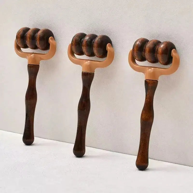 Three wooden massage roller tools with dark brown handles and lighter tan roller heads, arranged against a plain light gray wall.