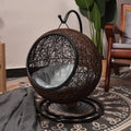 Wicker egg chair on a stand in a room with a plant and another chair.