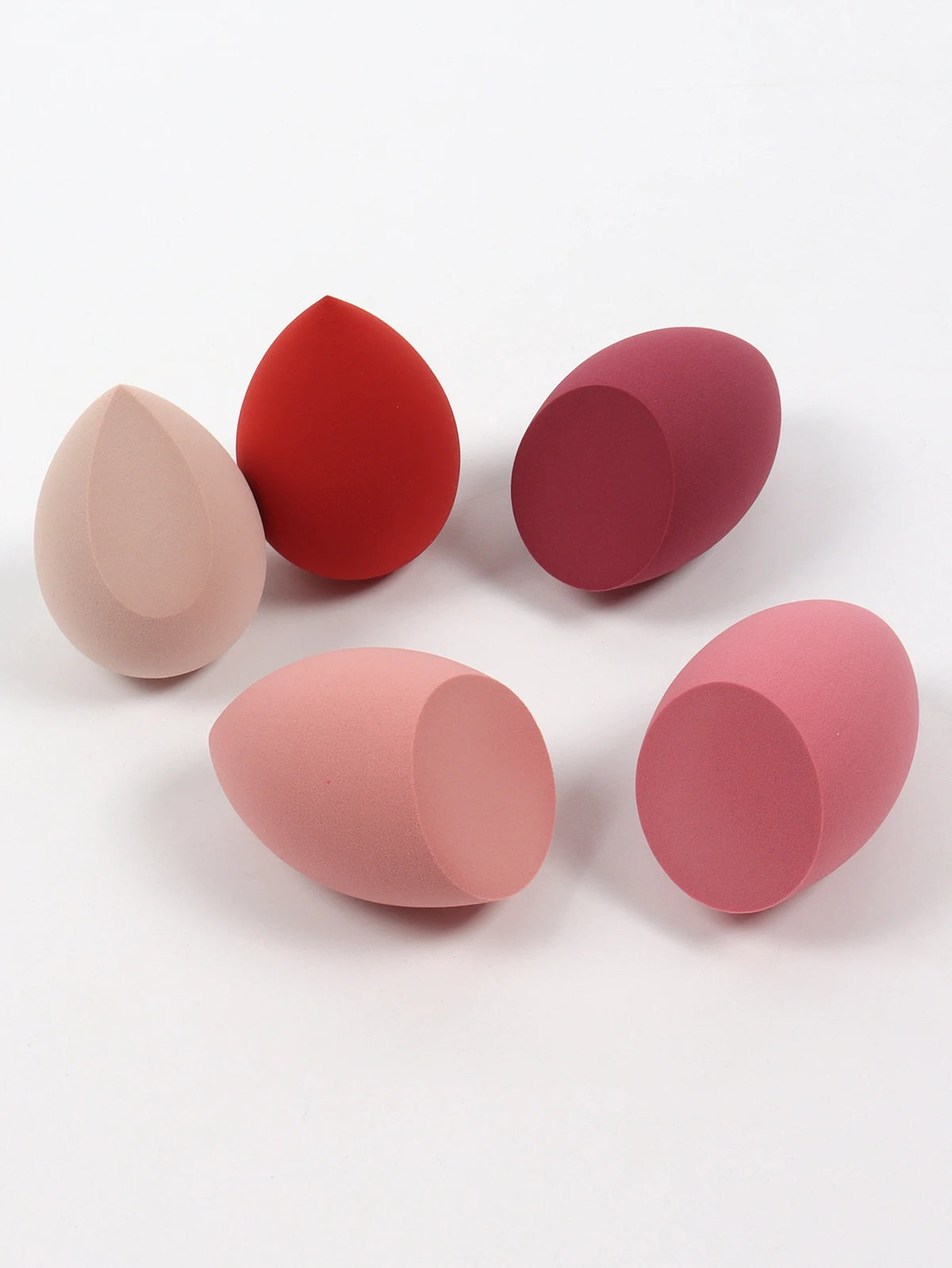 Set of five makeup sponges in various colors on a white background
